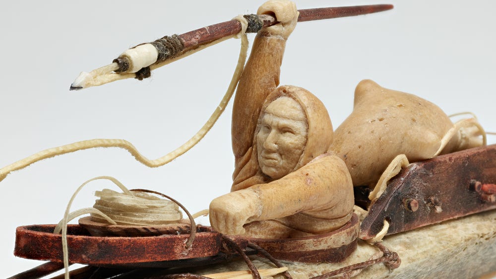 Sculpture of a person inside a kayak holding a spear
