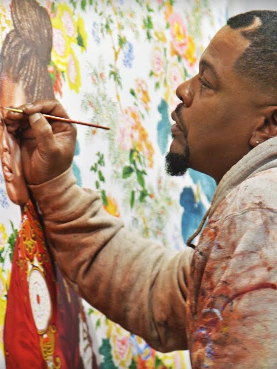 Kehinde Wiley holding a paint brush to a painting